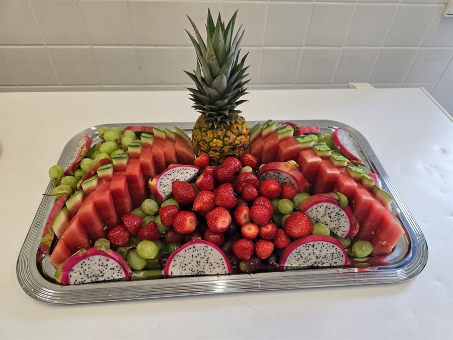 Obstplatte mit Ananas, Erdbeeren, Melone, Trauben und Drachenfrucht