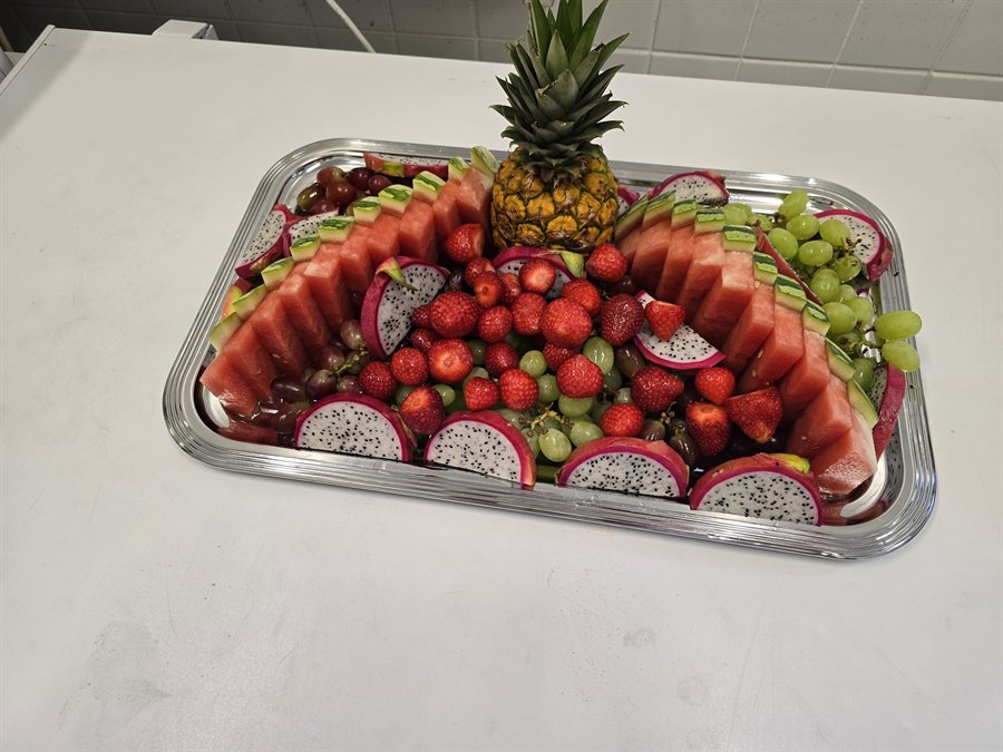 Dekorative Obstplatte mit Ananas, Melone, Erdbeeren und Drachenfrucht
